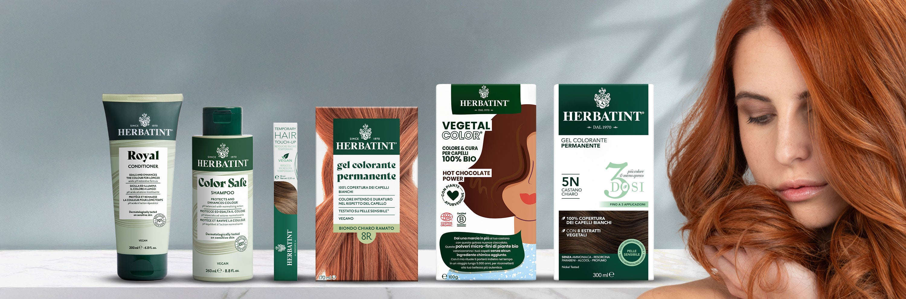 Linea completa di prodotti Herbatint su fondo neutro: shampoo, balsamo, mascara per capelli, gel coloranti permanenti e vegetal color; a destra donna con lunghi capelli ramati.